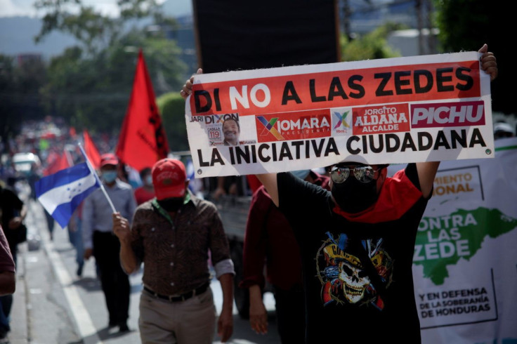 A demonstrator holds up a banner during a protest against the Zones for Employment and Economic Development (ZEDEs) and the government of Honduran President Juan Orlando Hernandez, in Tegucigalpa, Honduras September 15, 2021. 