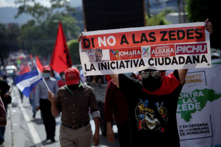 A demonstrator holds up a banner during a protest against the Zones for Employment and Economic Development (ZEDEs) and the government of Honduran President Juan Orlando Hernandez, in Tegucigalpa, Honduras September 15, 2021.