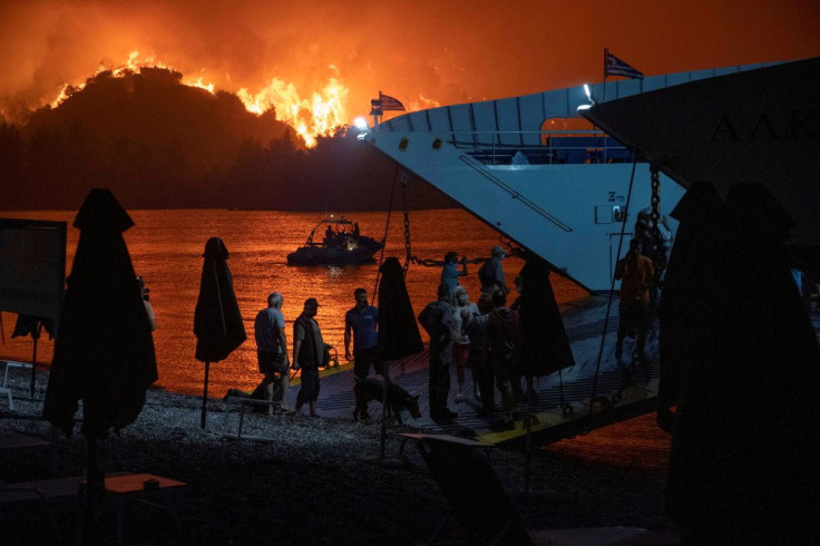 People board a ferry during evacuation as a wildfire burns in the village of Limni, on the island of Evia, Greece, August 6, 2021.
