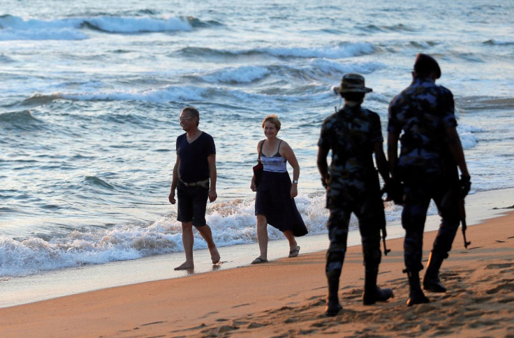 Tourists walk on a beach as Sri Lanka's military patrol the area as part of security measures after April 21 Easter Sunday bomb attacks on hotels and churches, in Colombo, Sri Lanka July 30, 2019. 