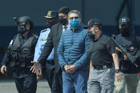 Honduras former President Juan Orlando Hernandez is escorted by authorities as he walks towards a plane of the U.S. Drug Enforcement Administration (DEA) for his extradition to the United States, to face a trial on drug trafficking and arms possession cha