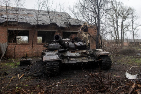 A Ukrainian soldier jumps of a destroyed Russian tank on the outskirts of the village of Mala Rohan, amid Russia's invasion of Ukraine, in Kharkiv region, Ukraine, April 20, 2022. Picture taken April 20, 2022. 