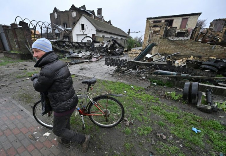 A man pushes his bicycle past a destroyed Russian armoured personnel carrier in the village of Gostomel, close to Kyiv on April 22, 2022