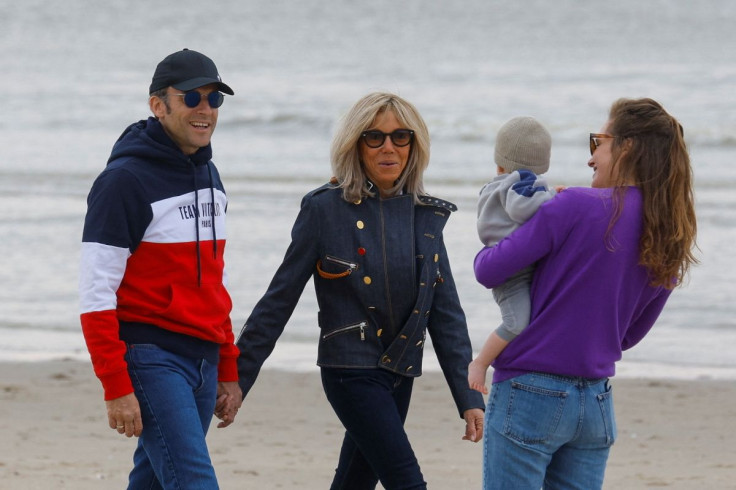 French President Emmanuel Macron, candidate for his re-election in the 2022 French presidential election, and his wife Brigitte Macron greet people as they walk on the beach, on the eve of the second round of the presidential election, in Le Touquet-Paris
