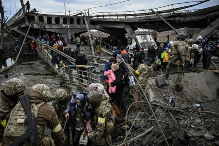 People cross a destroyed bridge as they evacuate the city of Irpin, northwest of Kyiv, during heavy shelling
