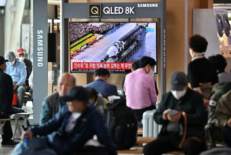People at a Seoul railway station watch a news broadcast of North Korea's military parade