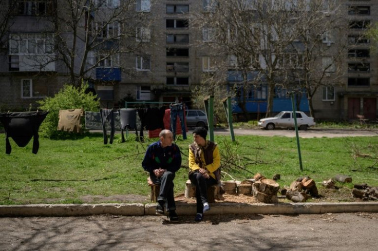 Residents sit outside an apartment complex damaged by shelling in the frontline town of Gulyaipole