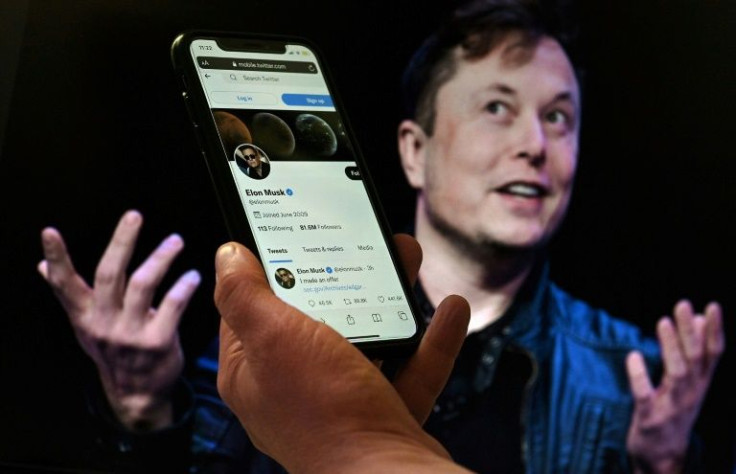 In this file photo taken on April 14, 2022 In this photo illustration, a phone screen displays the Twitter account of Elon Musk with a photo of him shown in the background, on April 14, 2022, in Washington, DC