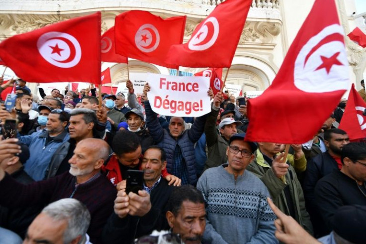 Tunisians raise national flags as they take to the streets of the capital Tunis to protest against their president on April 10, 2022