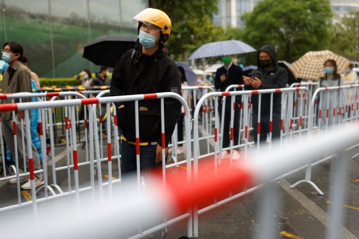 Residents line up in the rain at a makeshift nucleic acid testing site amid a mass testing for the coronavirus disease (COVID-19) in Chaoyang district of Beijing, China April 27, 2022.