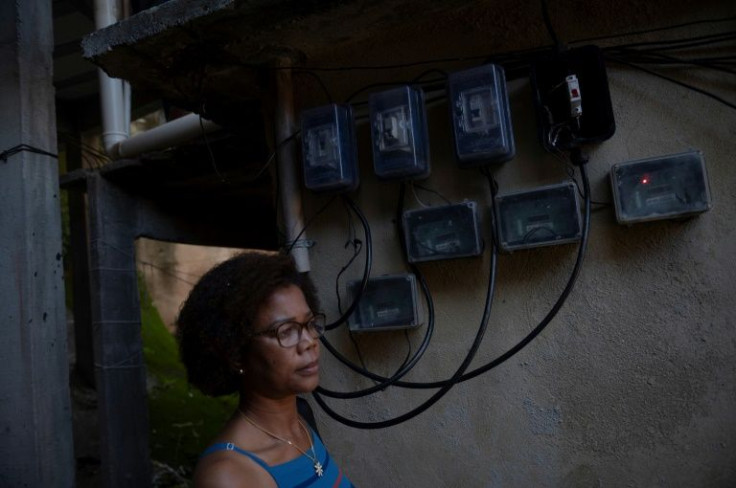 Marcia Campos, one of the participants in Babilonia favela's solar co-op, stands next to the power meter on her home