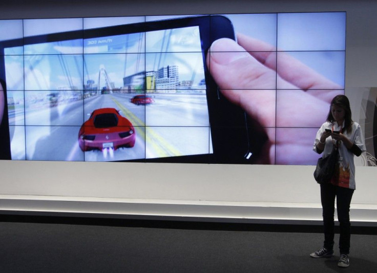 A visitor uses her mobiles while standing in front of a big screen displaying an Android tablet from Samsung