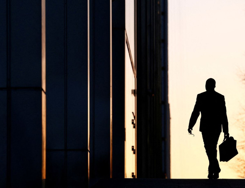 A worker arrives at his office in the Canary Wharf business district in London February 26, 2014. 