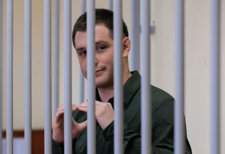 U.S. ex-Marine Trevor Reed, who was detained in 2019 and accused of assaulting police officers, gestures inside a defendants' cage during a court hearing in Moscow, Russia March 11, 2020. 