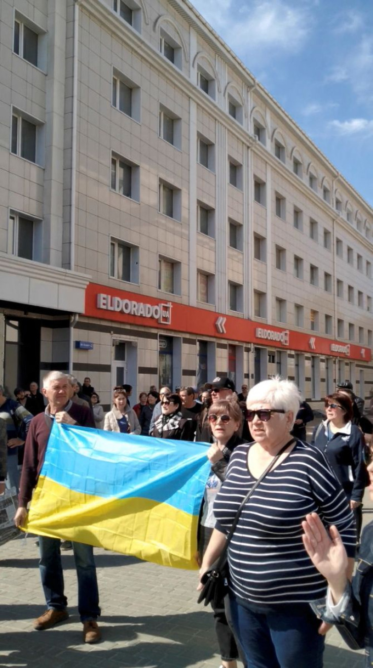 People hold Ukraine's national flag during a protest where tear gas was fired on them, amid Russia's invasion of Ukraine, in Kherson, Ukraine April 27, 2022 in this still image obtained by REUTERS from a social media video.  