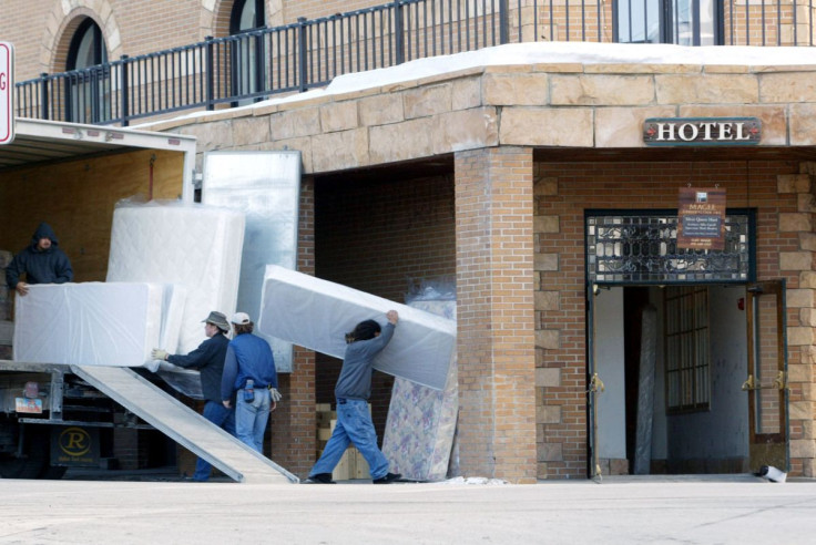 Workers carry mattresses into a hotel in downtown Park City, Utah January 23, 2002.
