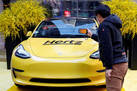 A man photographs a Hertz Tesla electric vehicle displayed during the Hertz Corporation IPO at the Nasdaq Market site in Times Square in New York City, U.S., November 9, 2021. 