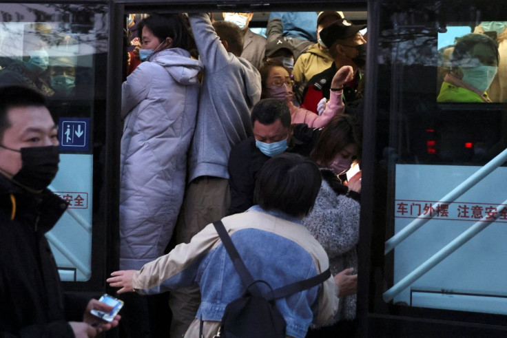 A woman attempts to get onto a bus with other commuters in the early morning, near a border checkpoint with Hebei province, following the coronavirus disease (COVID-19) outbreak, in Beijing, China April 13, 2022. Picture taken April 13, 2022.