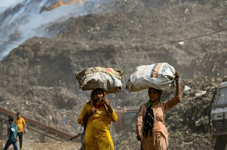 Ragpickers carrying sacks walk near New Delhi's Bhalaswa landfill, which has been on fire for three days