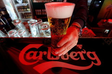A bartender holds a glass of Carlsberg beer in a bar in St. Petersburg June 17, 2014. 