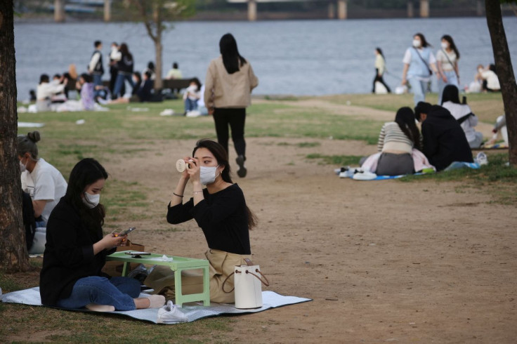A woman wearing a mask, amid the coronavirus disease (COVID-19) pandemic, adjusts her makeup at a Han river park in Seoul, South Korea, April 26, 2022. 