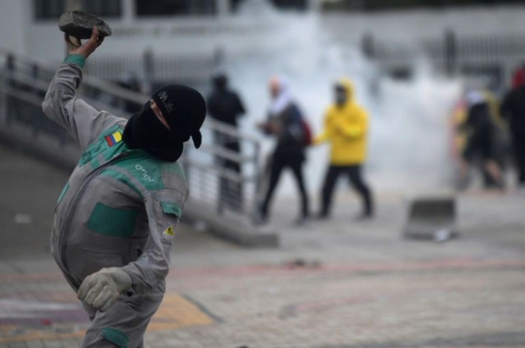 A demonstrator throws a stone at riot police during clashes outside National University in Bogota, on April 28, 2022