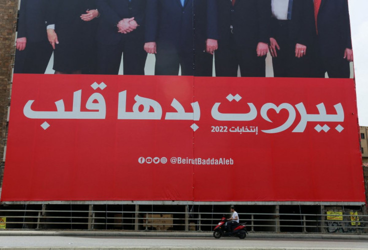 A man rides a motorbike near an electoral campaign sign that reads "Beirut needs a heart" ahead of the parliamentary election that is scheduled for May 15, in Beirut Lebanon April 18, 2022. Picture taken April 18, 2022.