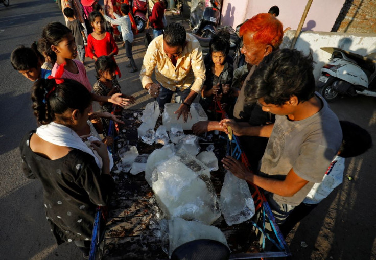 A man breaks a block of ice to distribute it among the residents of a slum during hot weather in Ahmedabad, India, April 28, 2022.