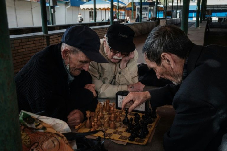 Elderly men play chess at an empty market in eastern Ukraine