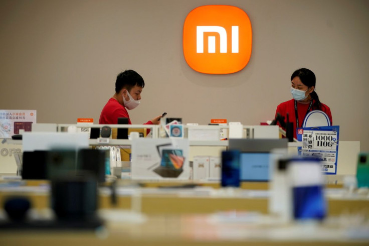 Staff members stand near the company logo at a Xiaomi store in Shanghai, China November 1, 2021.