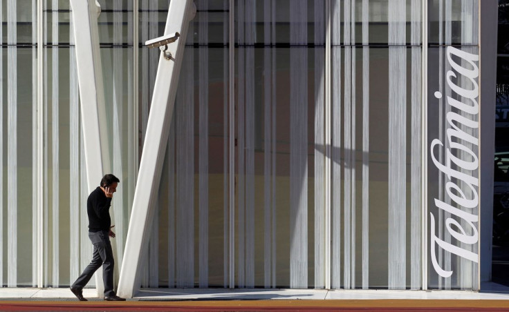 A man speaks by a mobile next to Telefonica's tower in Barcelona January 30, 2013.