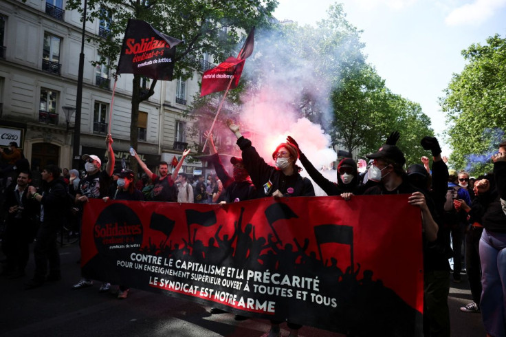 Masked protesters walk with a banner during the traditional May Day labour union march in Paris, France, May 1, 2022. 