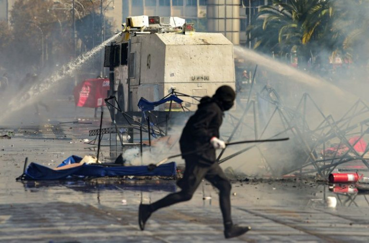 Riot police disperse demonstrators with a water cannon during clashes following a May Day march in Santiago