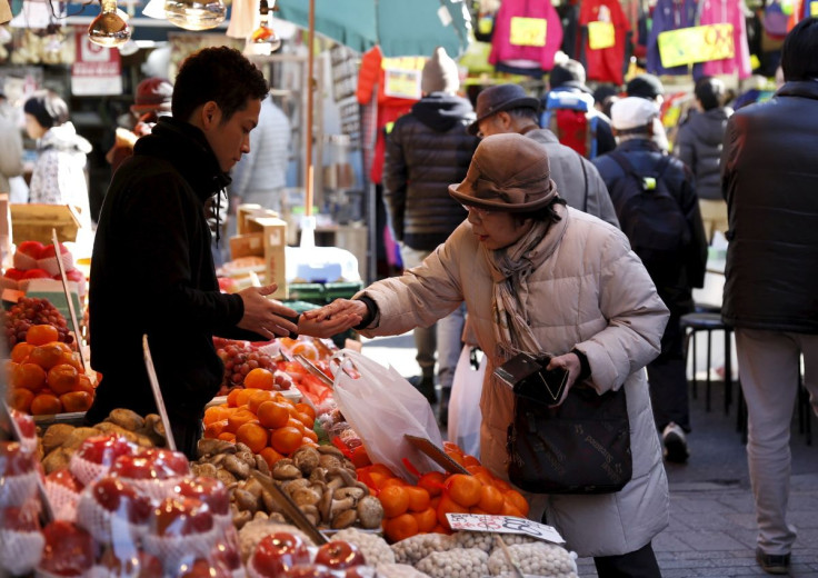 A woman pays money as she buys fruits outside a vegetable store at Ameyoko shopping district in Tokyo, Japan, January 27, 2016. J