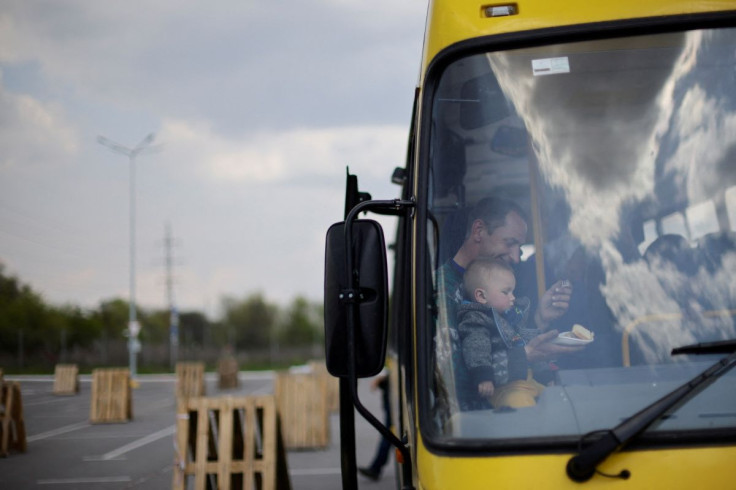 A Ukrainian refugee from Zaporizhzhia region feeds his son after arriving at a registration center for internally displaced people, amid Russia's invasion of Ukraine, in Zaporizhzhia, Ukraine May 2, 2022.