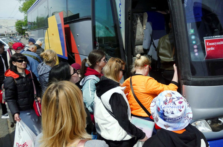 People board a bus as refugees from southeastern Ukraine, who are preparing to travel to the Palanca checkpoint to cross into Moldova en route to Germany, gather in Odesa, Ukraine, May 3, 2022.  