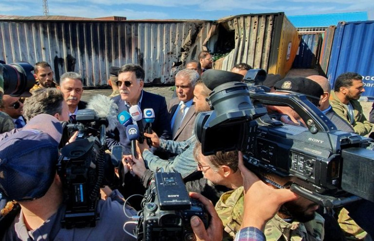 Libya's then-prime minister Fayez al-Sarraj, flanked by journalists, visits Tripoli port after it was hit by rocket fire on February 19, 2020