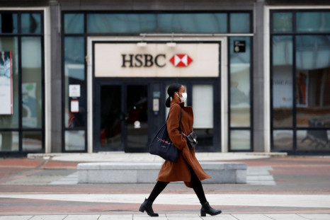 A woman wearing a protective face mask walks past a logo of HSBC bank at the financial and business district of La Defense near Paris as France begun a gradual end to a nationwide lockdown due to the coronavirus disease (COVID-19), May 11, 2020. 