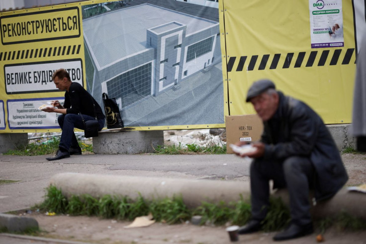 Ukrainian evacuees eat while people stand for aid at a donation collection point, amid Russia's invasion of Ukraine, in Zaporizhzhia, Ukraine May 4, 2022. 
