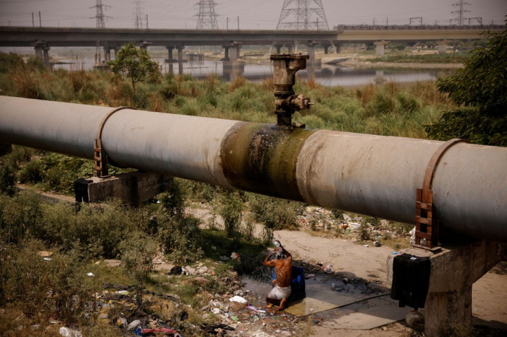 A man bathes under a broken water pipeline on a hot summer day in New Delhi, India, May 2, 2022.