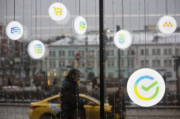 A man walks past an office of the Russian largest lender Sberbank in Moscow, Russia December 24, 2020. The logos of Sberbank ecosystem companies, which launched campaigns and new market, delivery, taxi and online cinema services, are displayed on an offic