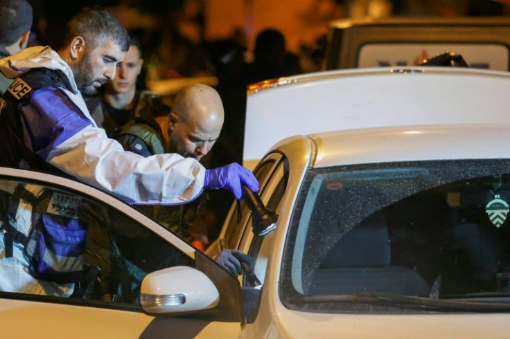 Israeli police examine a car following an attack in the cetral city of Elad in which at least three people were killed