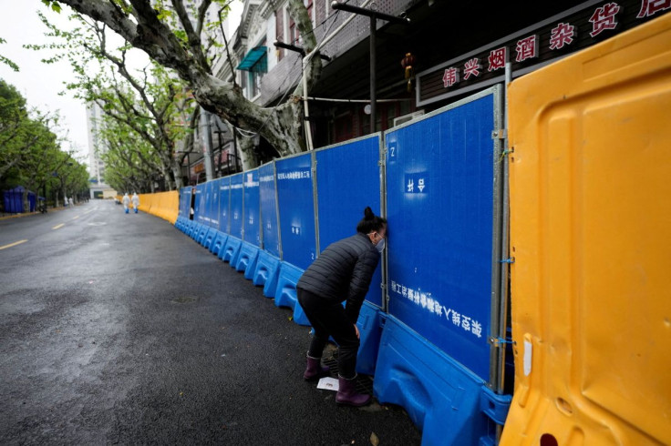 A woman tries to buy food from a vendor behind barricades of a sealed-off area, during lockdown amid the coronavirus disease (COVID-19) pandemic, in Shanghai, China April 14, 2022.