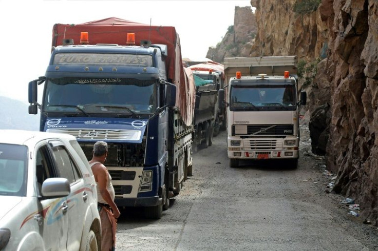 Trucks travel along a heavily damaged road, the only route between Yemen's cities of Taez and Aden
