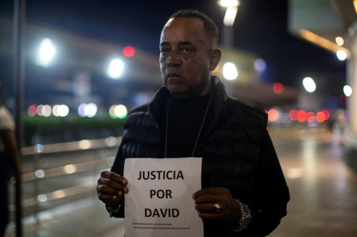 Cesar Ozuna, the father of David de los Santos, holds up a sign saying 'Justice for David' during a protest against his son's death