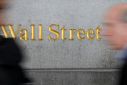 People walk by a Wall Street sign close to the New York Stock Exchange (NYSE) in New York, U.S., April 2, 2018. 