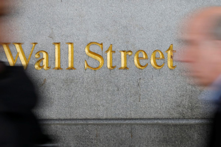 People walk by a Wall Street sign close to the New York Stock Exchange (NYSE) in New York, U.S., April 2, 2018. 