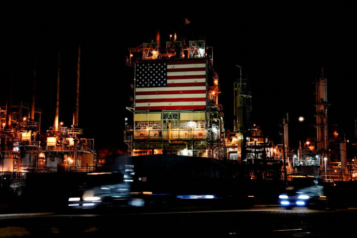 Semi trucks drive past a giant U.S. flag displayed at Marathon Petroleum's Los Angeles Refinery in Carson, California, U.S., March 11, 2022. Picture taken with long exposure.