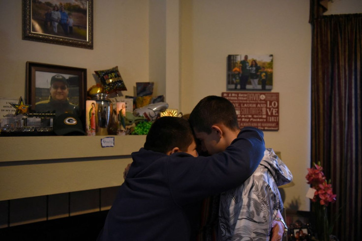 Aidan Garza, 12, (L) Julius Garza, 14, (R) and Margaret Garza (C) pray together next to their fatherâs urn, which they call "the vessel," in Converse, Texas, U.S March 30, 2022. Margaret made sure that her sons had counselling after their dad died. "Our
