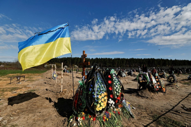 Ukraine's flag is see beside new graves for people killed during Russia's invasion of Ukraine, at a cemetery in Bucha Kyiv region, Ukraine April 28, 2022. 